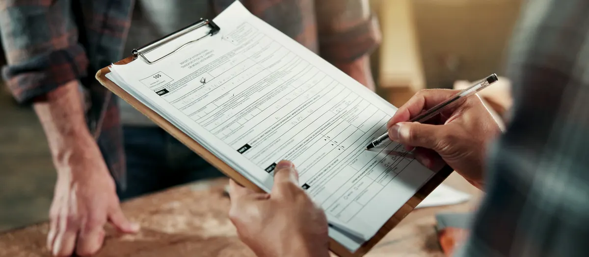 Two people at a workbench going through a printed checklist on a clipboard.